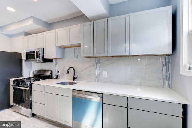 2915 Baker St, Baltimore, MD 21216 - kitchen featuring stainless steel appliances, a sink, tasteful backsplash, light countertops, and gray cabinetry
