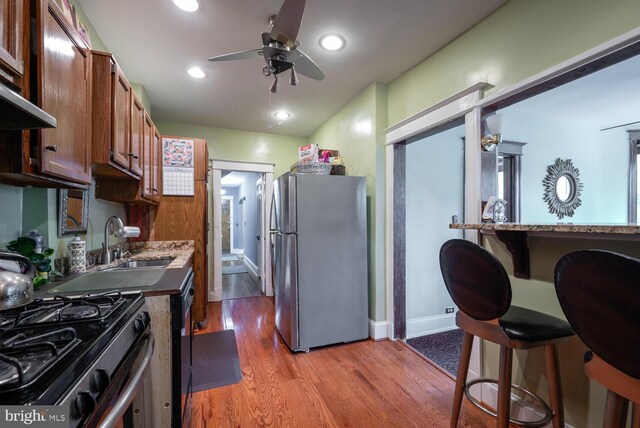 4800 Illinois Ave NW, Washington, DC 20011 - kitchen with stainless steel appliances, a ceiling fan, a sink, light wood-style floors, and baseboards