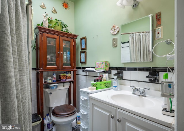 4800 Illinois Ave NW, Washington, DC 20011 - bathroom with tile walls, vanity, toilet, wainscoting, and a shower with shower curtain