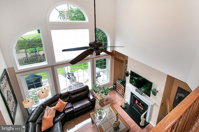 13763 Deacons Way, Gainesville, VA 20155 - living area with a towering ceiling, ceiling fan, a warm lit fireplace, and wood finished floors
