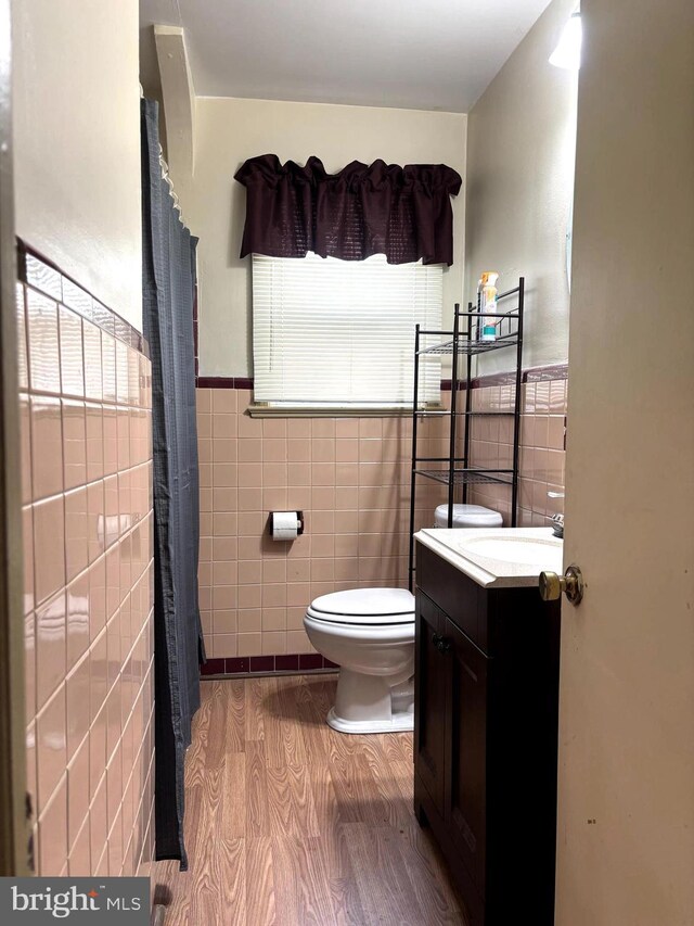 423 S E Ave, Bridgeton, NJ 08302 - bathroom featuring tile walls, wood finished floors, toilet, vanity, and wainscoting