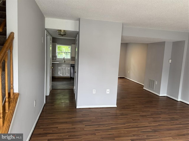 15368 Blacksmith Ter, Woodbridge, VA 22191 - empty room with dark wood-style floors, baseboards, a textured ceiling, a chandelier, and a sink