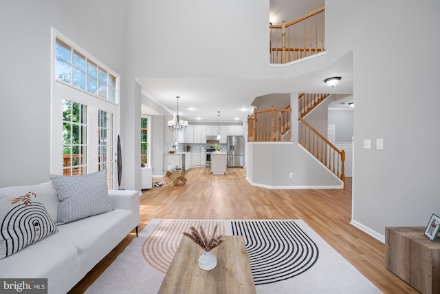 47561 Hidden Cove Ct, Sterling, VA 20165 - living room featuring a high ceiling, light wood-style floors, stairs, baseboards, and a chandelier