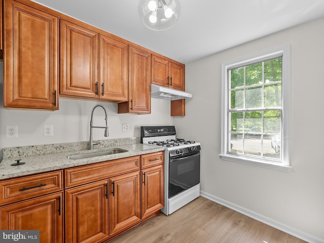 6727 W Wakefield Dr Unit A2, Alexandria, VA 22307 - kitchen featuring gas range gas stove, a sink, under cabinet range hood, light wood-style flooring, and brown cabinetry