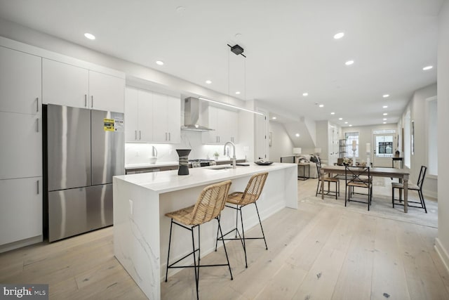 1744 Lanier Pl NW Unit 1, Washington, DC 20009 - kitchen featuring freestanding refrigerator, wall chimney exhaust hood, a sink, light wood-style flooring, and white cabinets