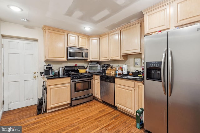 766 S 18th St, Philadelphia, PA 19146 - kitchen with appliances with stainless steel finishes, a sink, light brown cabinets, dark countertops, and light wood-style floors