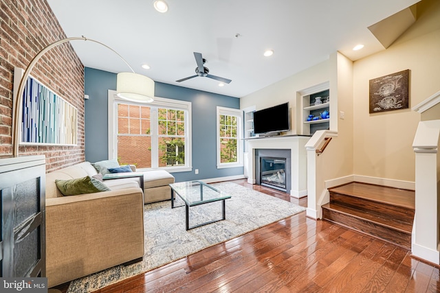 585 Regent Pl NE, Washington, DC 20017 - living area featuring a ceiling fan, hardwood / wood-style flooring, a glass covered fireplace, baseboards, and brick wall