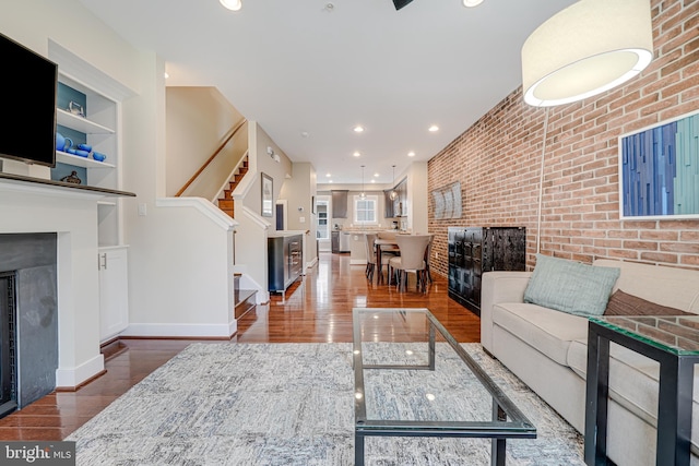 585 Regent Pl NE, Washington, DC 20017 - living area with a fireplace, stairway, wood finished floors, brick wall, and baseboards