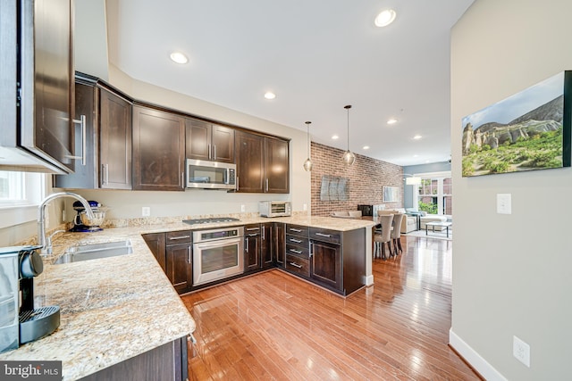 585 Regent Pl NE, Washington, DC 20017 - kitchen featuring stainless steel appliances, a sink, dark brown cabinetry, a peninsula, and light stone countertops