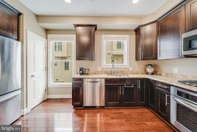 585 Regent Pl NE, Washington, DC 20017 - kitchen featuring appliances with stainless steel finishes, a sink, dark wood-style flooring, dark brown cabinetry, and light stone counters