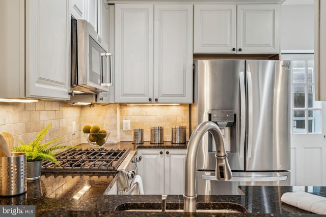 314 Monroe St, Philadelphia, PA 19147 - kitchen featuring appliances with stainless steel finishes, white cabinets, tasteful backsplash, dark stone countertops, and a sink
