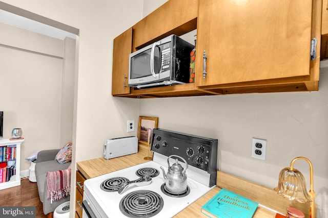 1725 New Hampshire Ave NW Unit 303, Washington, DC 20009 - kitchen view of stainless steel microwave, electric range oven, brown cabinetry, and light countertops