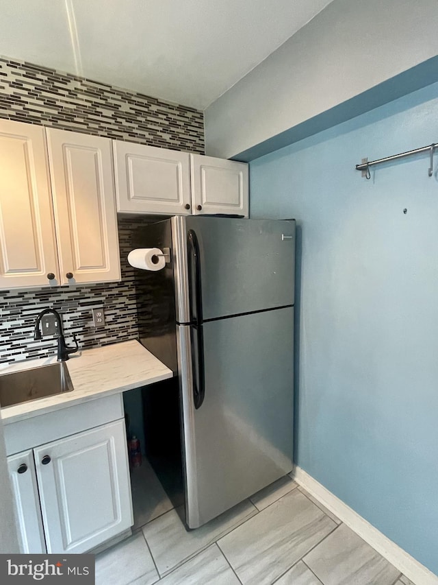 3401 Commonwealth Ave Unit A, Alexandria, VA 22305 - kitchen with freestanding refrigerator, a sink, white cabinets, backsplash, and light countertops