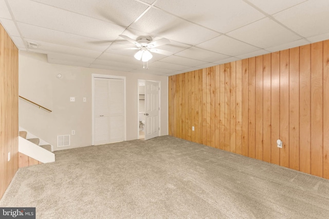 2053 Wintergreen Pl, Rosedale, MD 21237 - unfurnished living room featuring carpet floors, wooden walls, a drop ceiling, stairway, and a ceiling fan