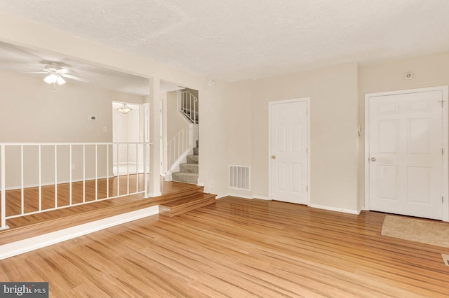 2053 Wintergreen Pl, Rosedale, MD 21237 - empty room featuring light wood-style flooring, ceiling fan, a textured ceiling, baseboards, and stairs