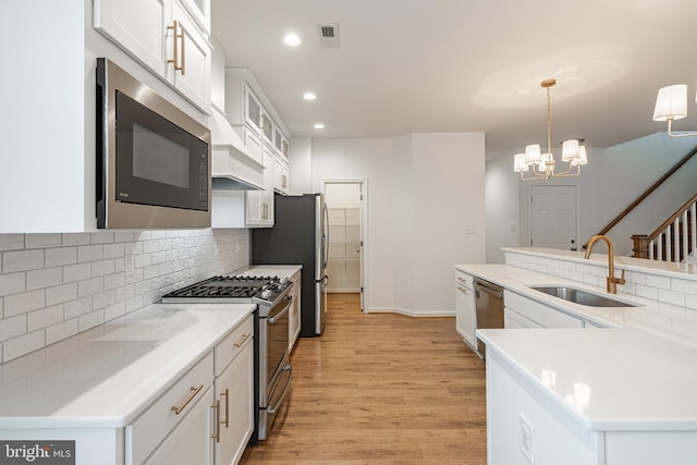4005 Sweet Azalea Row, Glen Allen, VA 23059 - kitchen featuring appliances with stainless steel finishes, a sink, light wood finished floors, decorative backsplash, and a chandelier