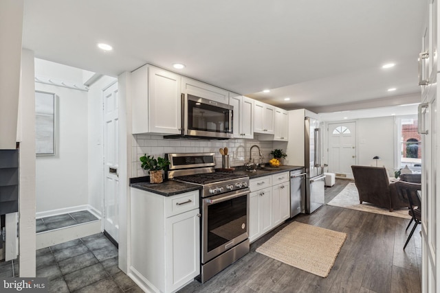 106 Bainbridge St, Philadelphia, PA 19147 - kitchen with stainless steel appliances, a sink, dark countertops, decorative backsplash, and white cabinetry