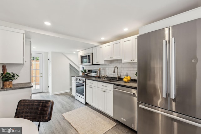 106 Bainbridge St, Philadelphia, PA 19147 - kitchen featuring appliances with stainless steel finishes, a sink, dark countertops, white cabinetry, and recessed lighting