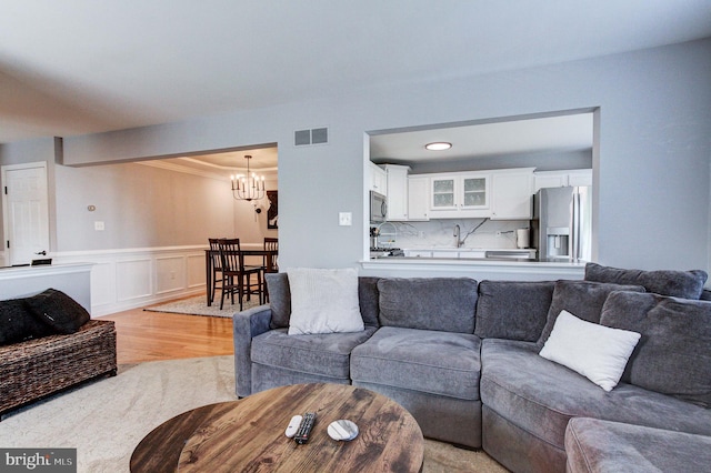 812 Red Rock Cir, Royersford, PA 19468 - living area with a chandelier, light wood-style flooring, wainscoting, ornamental molding, and a decorative wall