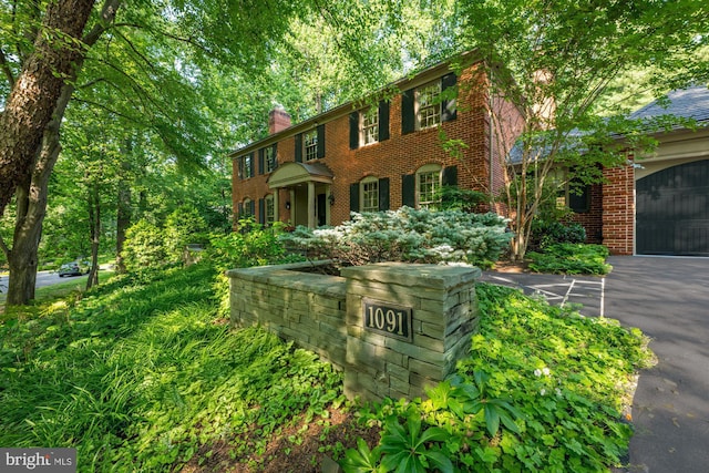 1091 Old Cedar Rd, Mclean, VA 22102 - view of front of property featuring brick siding, a chimney, and driveway