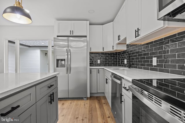 1 Mimosa Ln, Levittown, PA 19054 - kitchen featuring appliances with stainless steel finishes, a sink, tasteful backsplash, light wood-type flooring, and hanging light fixtures