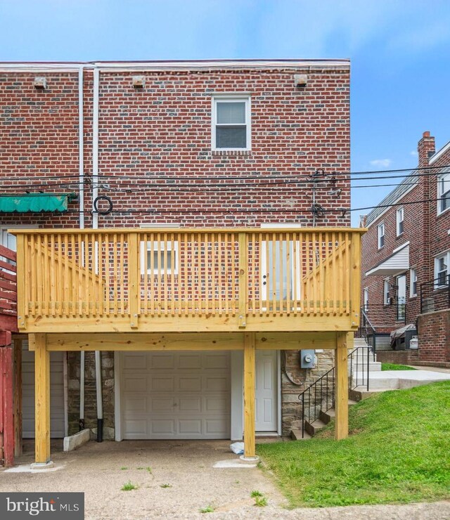 937 E Durard St, Philadelphia, PA 19150 - back of house with an attached garage, a wooden deck, driveway, brick siding, and stone siding