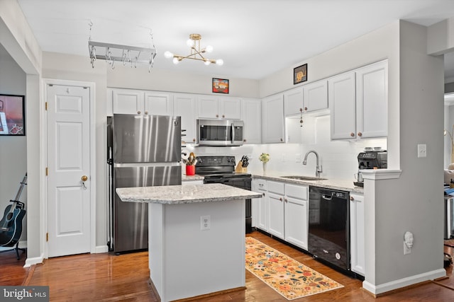 12794 Silvia Loop, Woodbridge, VA 22192 - kitchen with black appliances, backsplash, white cabinetry, a center island, and wood finished floors