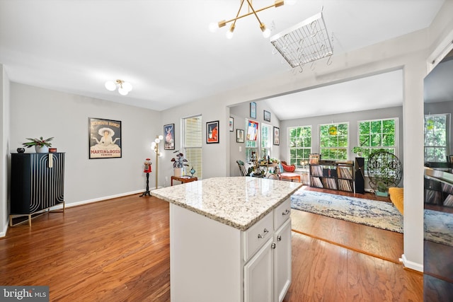12794 Silvia Loop, Woodbridge, VA 22192 - kitchen with a kitchen island, light stone counters, wood finished floors, white cabinetry, and open floor plan