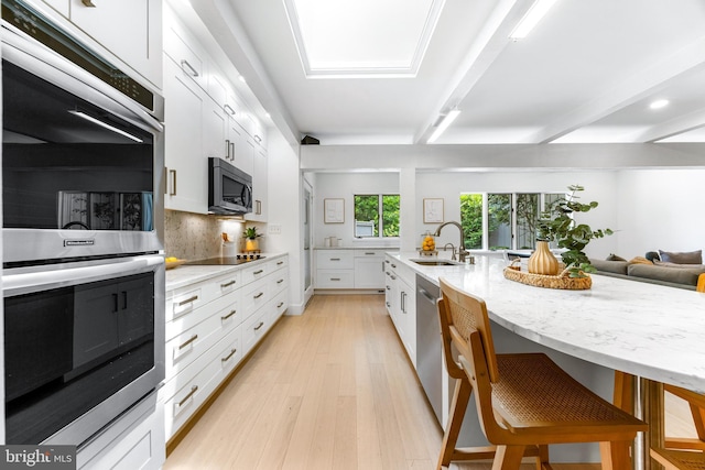 5 Tall Tree Ct, Baltimore, MD 21208 - kitchen with appliances with stainless steel finishes, tasteful backsplash, white cabinets, light wood-style floors, and light stone countertops