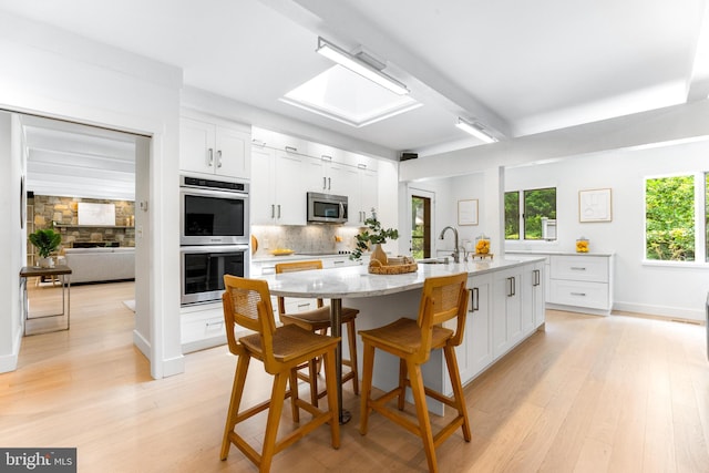 5 Tall Tree Ct, Baltimore, MD 21208 - kitchen featuring appliances with stainless steel finishes, decorative backsplash, light wood-style floors, and white cabinetry