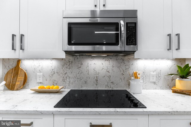 5 Tall Tree Ct, Baltimore, MD 21208 - kitchen featuring stainless steel microwave, black electric stovetop, white cabinetry, and backsplash