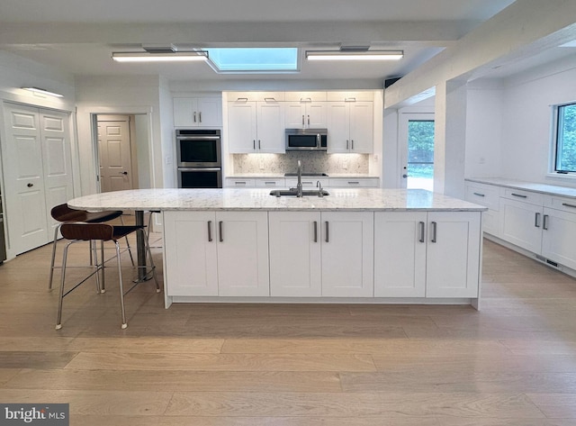 5 Tall Tree Ct, Baltimore, MD 21208 - kitchen with appliances with stainless steel finishes, white cabinetry, and light wood-style floors