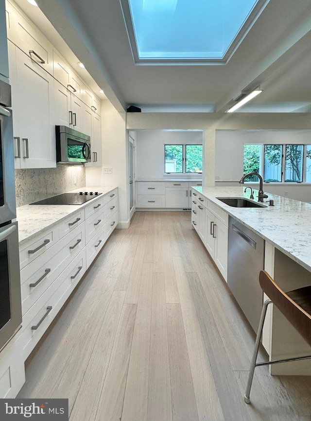 5 Tall Tree Ct, Baltimore, MD 21208 - kitchen with appliances with stainless steel finishes, light stone counters, light wood-style flooring, white cabinets, and decorative backsplash