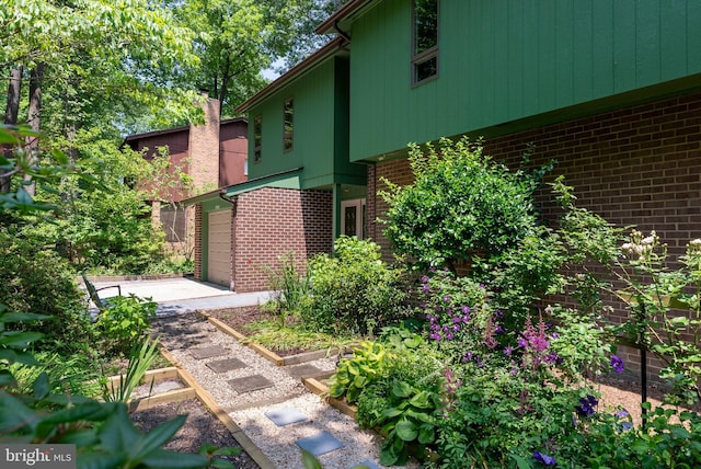 5305 Thunder Hill Rd, Columbia, MD 21045 - view of property exterior featuring brick siding, driveway, a vegetable garden, and an attached garage