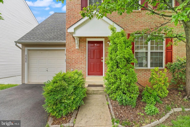 45620 Livingstone Station St, Sterling, VA 20166 - property entrance with brick siding, an attached garage, roof with shingles, asphalt driveway, and a chimney
