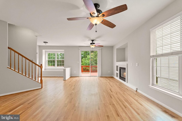 45620 Livingstone Station St, Sterling, VA 20166 - unfurnished living room featuring light wood-type flooring, a ceiling fan, a glass covered fireplace, and stairs