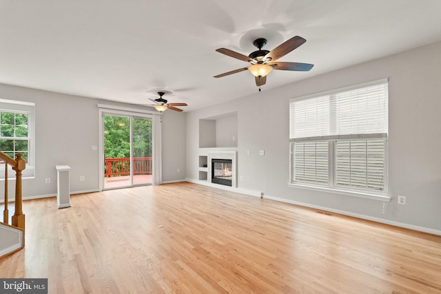 45620 Livingstone Station St, Sterling, VA 20166 - unfurnished living room with light wood-style floors, ceiling fan, baseboards, and a glass covered fireplace
