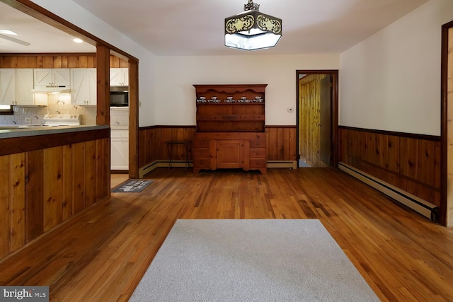 172 Chippewa Trl, Medford Lakes, NJ 08055 - unfurnished dining area with baseboard heating, a baseboard radiator, wainscoting, wood finished floors, and wooden walls