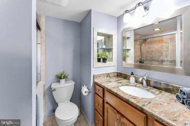 full bathroom with vanity, a tile shower, toilet, and tile patterned flooring