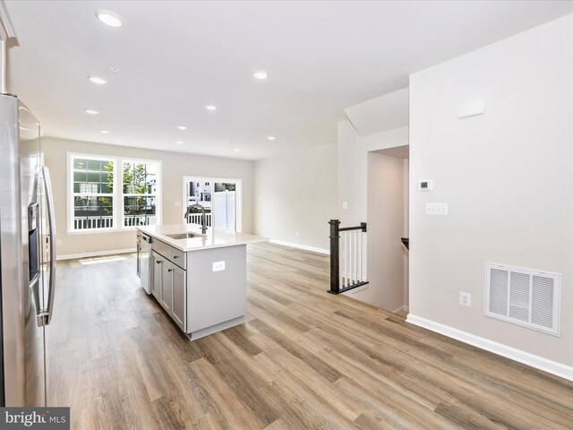 108 Spring Bank Way, Frederick, MD 21701 - kitchen featuring stainless steel appliances, light wood-style floors, gray cabinets, light countertops, and a kitchen island with sink