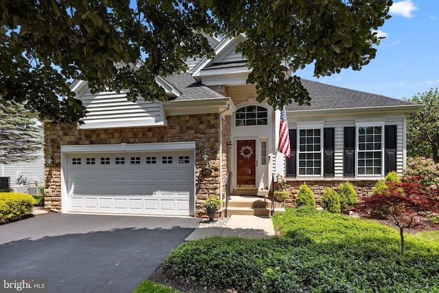 230 Bobwhite Rd, New Hope, PA 18938 - view of front of home with stone siding, asphalt driveway, a shingled roof, central air condition unit, and a garage