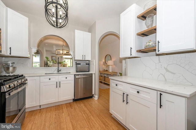 2500 Waterside Dr Unit 110, Frederick, MD 21701 - kitchen featuring stainless steel appliances, open shelves, arched walkways, a chandelier, and light wood-type flooring