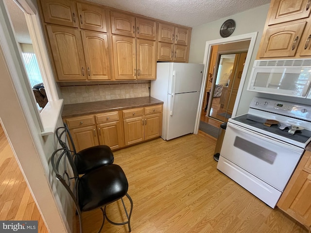 666 W Germantown Pike Unit 1721, Plymouth Meeting, PA 19462 - kitchen featuring white appliances, a textured ceiling, dark countertops, decorative backsplash, and light wood-style flooring