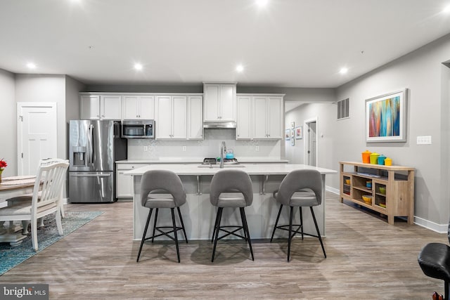 1528 Catbriar Way, Odenton, MD 21113 - kitchen with appliances with stainless steel finishes, under cabinet range hood, a kitchen island with sink, light countertops, and backsplash