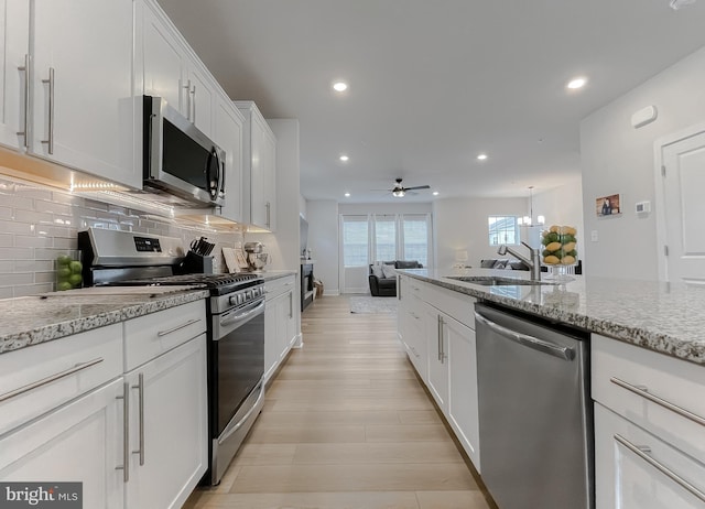 45375 Concord Way, California, MD 20619 - kitchen featuring stainless steel appliances, a sink, decorative backsplash, white cabinets, and light wood finished floors