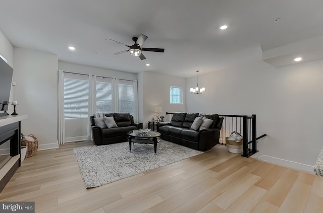 45375 Concord Way, California, MD 20619 - living area featuring light wood-style flooring, a ceiling fan, a chandelier, baseboards, and a glass covered fireplace