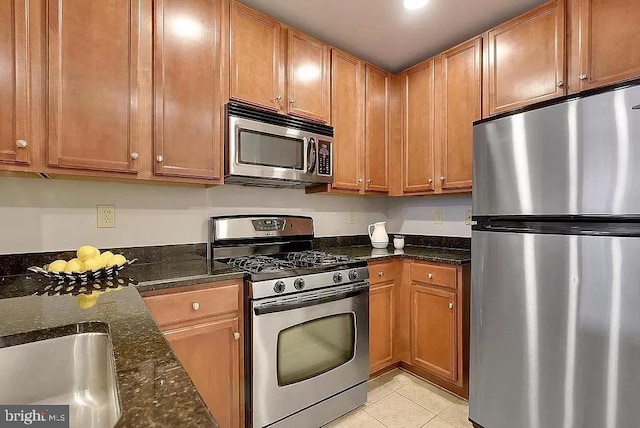 2665 Prosperity Ave Unit 6, Fairfax, VA 22031 - kitchen with appliances with stainless steel finishes, light tile patterned floors, dark stone countertops, and brown cabinets
