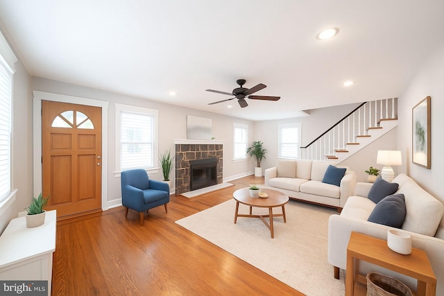 27 Shelbourne Rd, Havertown, PA 19083 - living room with light wood-style floors, a stone fireplace, stairway, a ceiling fan, and recessed lighting