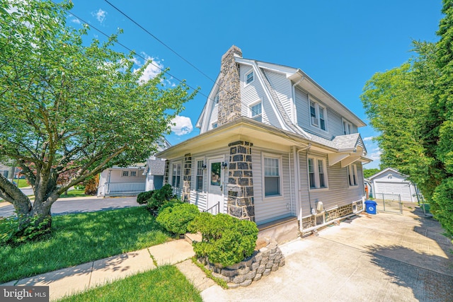 27 Shelbourne Rd, Havertown, PA 19083 - view of front of home with an outdoor structure, a detached garage, a chimney, concrete driveway, and a front lawn