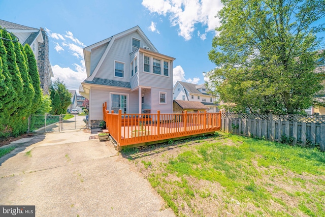 27 Shelbourne Rd, Havertown, PA 19083 - back of property with a gate, a fenced backyard, a wooden deck, a gambrel roof, and driveway